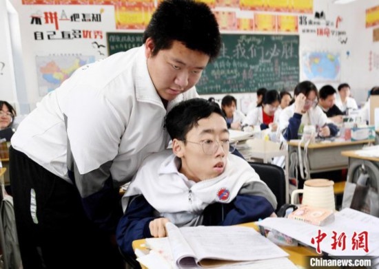 朱金祥(左)把鐘華強(qiáng)放到課堂座位上后，都要把他擺正好，確認(rèn)安全后才回到自己的座位上。 卓忠偉 攝