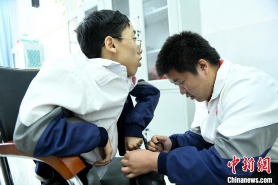 江西省南康中學(xué)北校區(qū)的高三學(xué)生朱金祥(右)正在給鐘華強(qiáng)(左)系好鞋帶。 卓忠偉 攝