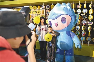 5月7日，在浙江省杭州市湖濱步行街“3D笑臉墻”前，攝影師為游客與杭州亞運(yùn)會(huì)吉祥物之一“宸宸”拍攝合影。