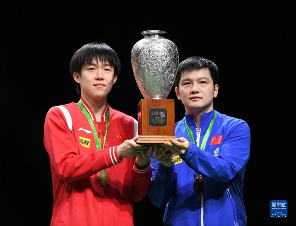 5月27日，樊振東（右）/王楚欽在頒獎儀式上高舉獎杯慶祝。當(dāng)日，在南非德班進行的2023年世界乒乓球錦標賽男雙決賽中，中國組合樊振東/王楚欽以3比0戰(zhàn)勝韓國組合張禹珍/林鐘勛，奪得冠軍。新華社記者 李亞輝攝