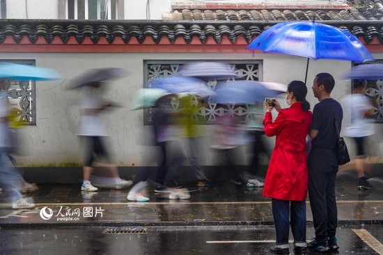 6月7日，在浙江省2023年普通高校招生考試鎮(zhèn)海中學(xué)考點(diǎn)，家長冒雨目送子女進(jìn)入考場。人民網(wǎng) 章勇濤攝