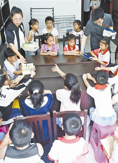  圖④：法院干警為留守兒童發(fā)放暑假讀物。