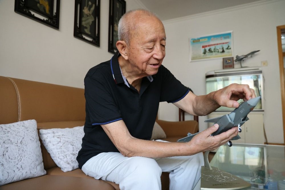 ↑2023年7月24日，新中國(guó)第一代飛行員陶偉在家中擦拭殲-20飛機(jī)模型。新華社發(fā)（張瑞 攝）