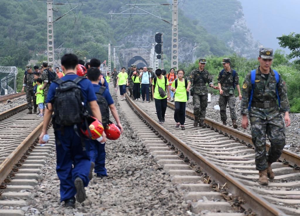 8月2日，部分滯留在北京市門頭溝山區(qū)受困列車的旅客，在救援人員幫助下前往轉(zhuǎn)運客車。新華社記者張晨霖 攝