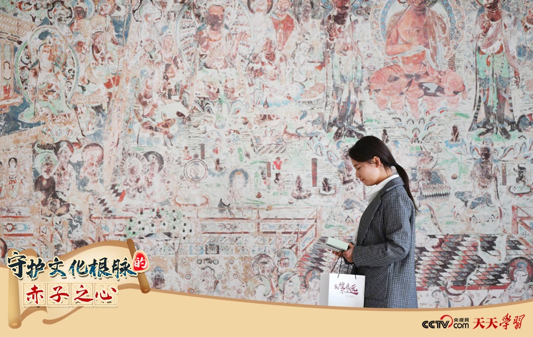 2023年4月25日，敦煌研究院文物數(shù)字化保護(hù)團(tuán)隊(duì)創(chuàng)意營(yíng)銷人員廖雪婷從一幅高保真復(fù)制壁畫前走過。