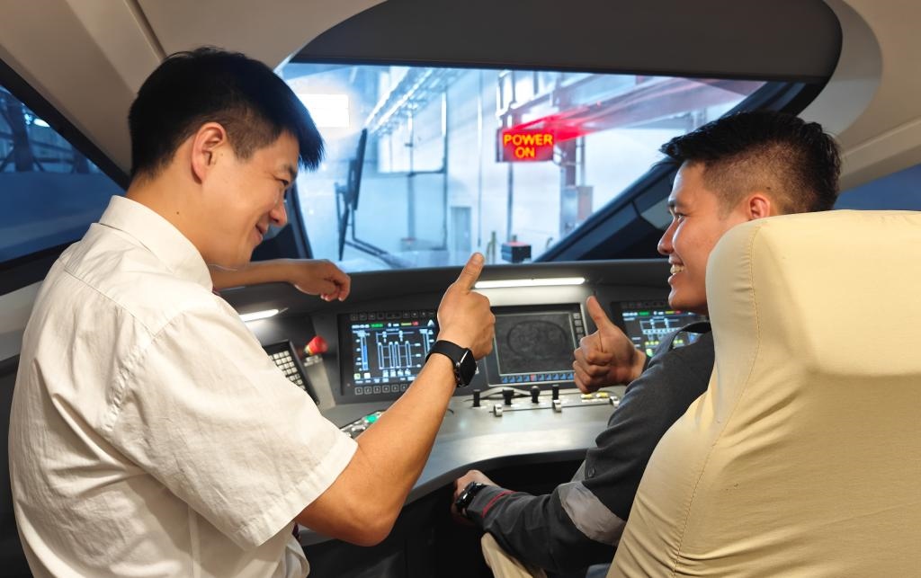 8月25日，在印度尼西亞萬隆的雅萬高鐵德卡魯爾動(dòng)車所內(nèi)，中國(guó)師傅穆振（左）在向印尼火車司機(jī)塞蒂亞萬講解動(dòng)車組出庫前的上電作業(yè)。