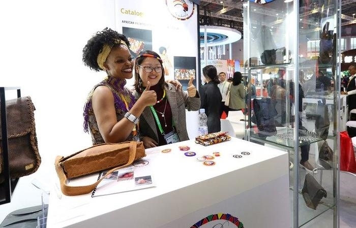 11月6日，一位參觀者（右）在第六屆進(jìn)博會(huì)國家展南非展臺(tái)試戴傳統(tǒng)首飾。