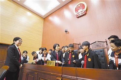 圖③：同學(xué)們穿法袍、敲法槌，爭做“小法官”。