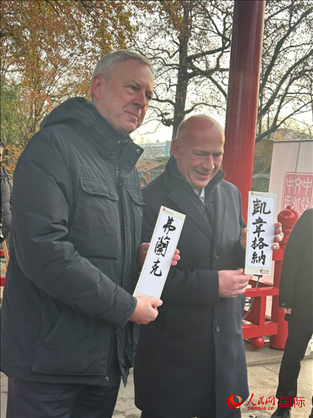 柏林市長韋格納（右）、動物園監(jiān)事會主席布魯克曼（左）手持中國文化中心工作人員現(xiàn)場手書的中文名字。人民網(wǎng)記者 徐馨攝