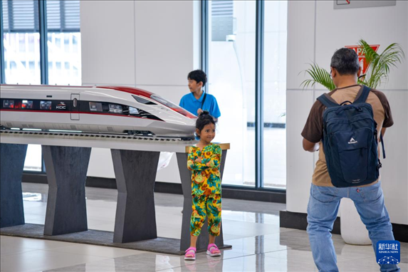 1月24日，在印度尼西亞雅加達(dá)哈利姆站候車大廳，一名小朋友和雅萬高鐵高速動車組模型合影。新華社記者 徐欽 攝