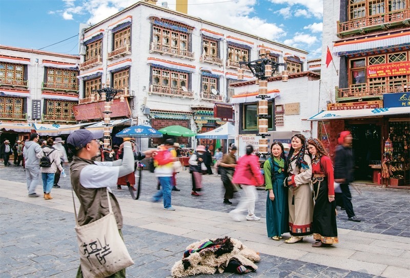 千年八廓街，見證民族團結。2021年7月，習近平總書記來到位于西藏拉薩老城區(qū)的八廓街，感慨地說：“千年八廓街，是我們各民族建起來的八廓街。各民族文化在這里交流交往交融，我們中華民族的大家庭在這里其樂融融?！眻D為2023年6月13日，游客身著藏裝在八廓街拍照留念。 新華社記者 姜帆/攝