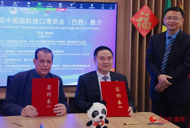 巴西外貿商會聯(lián)合會會長阿代爾·羅伯托（左）與中國國際進口博覽局副局長吳政平（中）現(xiàn)場簽訂協(xié)議。人民網記者 宋亦然攝