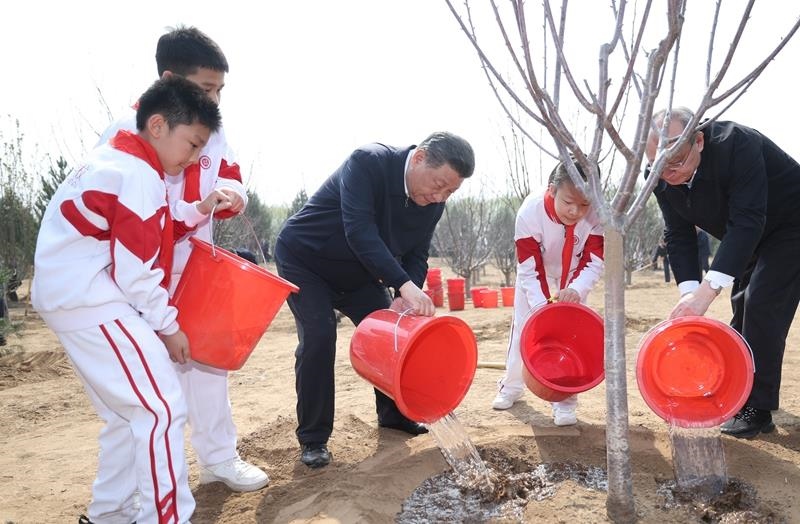 2024年4月3日，習(xí)近平總書記同少先隊(duì)員一起給剛栽下的樹苗澆水。