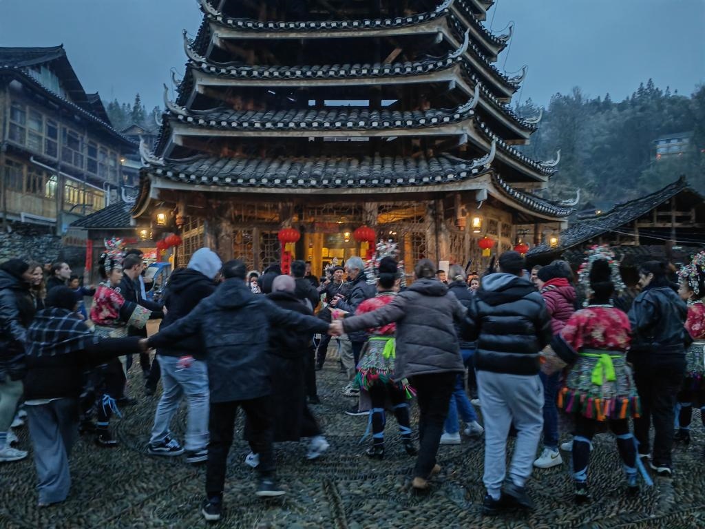 法國青年與當(dāng)?shù)卮迕駹渴痔?。新華社記者 羅羽 攝