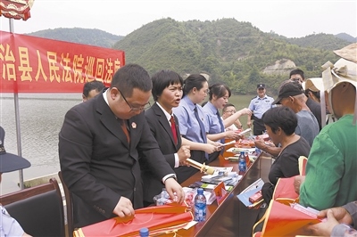 法院干警及相關(guān)部門工作人員對(duì)群眾進(jìn)行生態(tài)環(huán)境保護(hù)普法教育。
