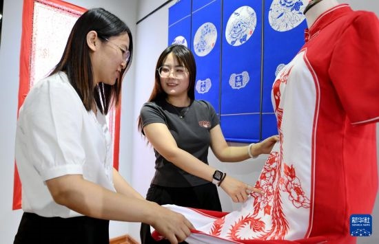 5月31日，在衡水市阜城縣一家剪紙工作室，游客在觀賞帶有剪紙元素的旗袍。