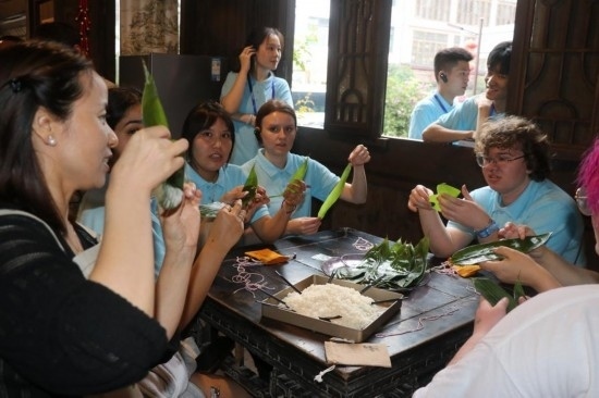 6月9日，美國(guó)青年代表在重慶永川松溉古鎮(zhèn)體驗(yàn)包粽子。新華社記者 周思宇 攝