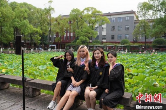 6月19日，時值一年畢業(yè)季，四川大學(xué)望江校區(qū)荷花池里的荷花盛開，成為了畢業(yè)生們的打卡圣地，吸引了眾多畢業(yè)生拍照留念。圖為畢業(yè)生在荷花池邊拍照留念。中新社記者 安源 攝