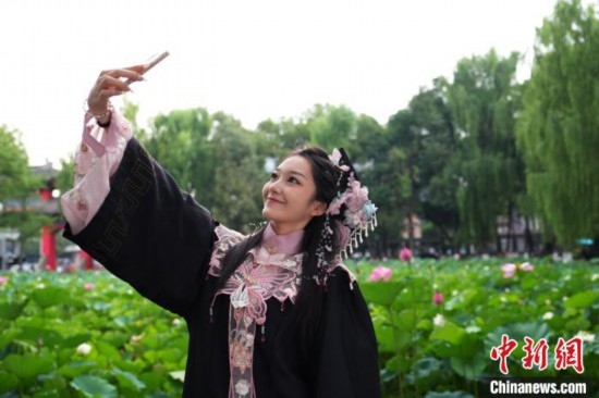 6月19日，時值一年畢業(yè)季，四川大學(xué)望江校區(qū)荷花池里的荷花盛開，成為了畢業(yè)生們的打卡圣地，吸引了眾多畢業(yè)生拍照留念。圖為畢業(yè)生在荷花池邊拍照留念。中新社記者 安源 攝