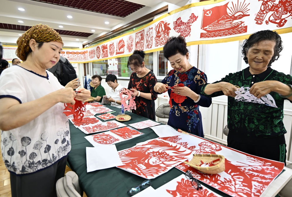 6月19日，長城花園社區(qū)居民在社區(qū)“才藝堂”制作剪紙。