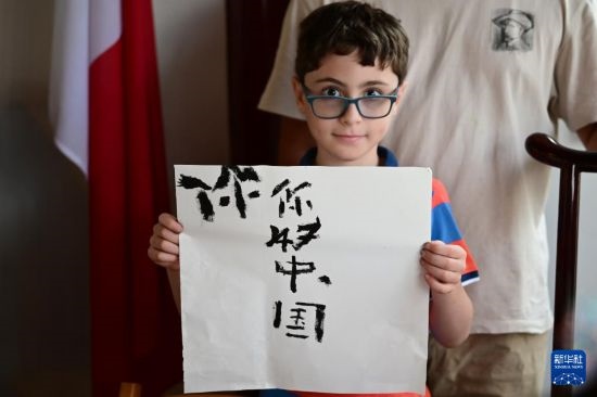 7月4日，在馬耳他桑塔露琪亞市的中國古典園林“靜園”，一名男孩展示他的書法作品。新華社發(fā)（喬納森·博格 攝）