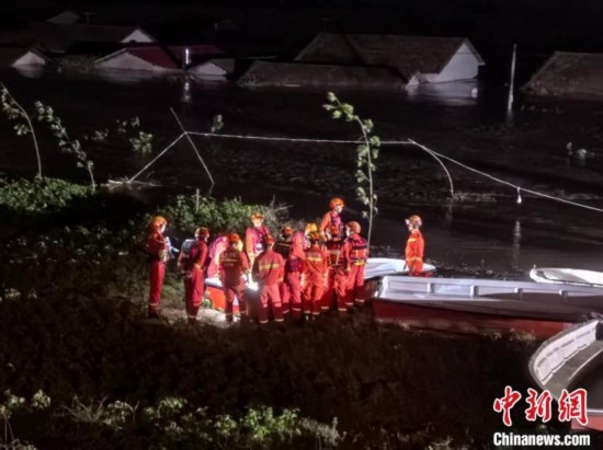  7月6日凌晨3時(shí)，在湖南岳陽(yáng)華容縣團(tuán)洲垸洞庭湖一線堤防，救援人員剛剛完成一次救援任務(wù)，遠(yuǎn)處是被淹的民房。中新社記者 白祖偕 攝