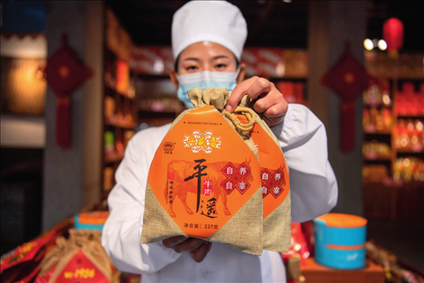 在位于山西省晉中市平遙縣的平遙古城南大街的一家平遙牛肉店內(nèi)，工作人員展示一款牛肉產(chǎn)品（資料照片）楊晨光攝 / 本刊