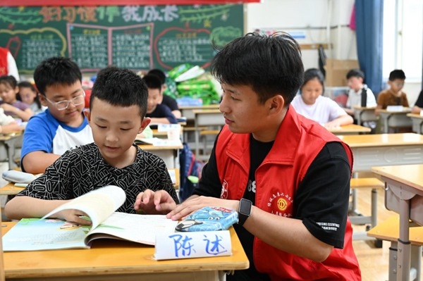 鄭州市二七區(qū)暑托班的志愿者輔導(dǎo)孩子寫(xiě)作業(yè)。人民網(wǎng)記者王玉興攝