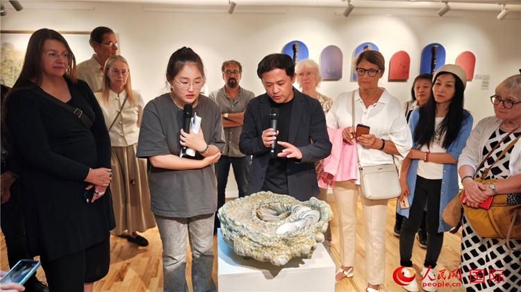 參展人、景德鎮(zhèn)陶瓷大學(xué)設(shè)計藝術(shù)學(xué)院副院長余劍峰（中）向來賓介紹參展作品。人民網(wǎng)記者 殷淼攝