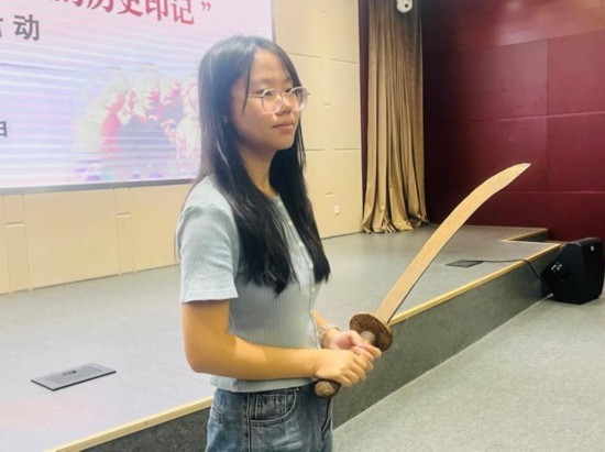 圖為南開大學(xué)社會(huì)實(shí)踐隊(duì)學(xué)生代表呼月紅在學(xué)術(shù)交流活動(dòng)現(xiàn)場(chǎng)，展示河間調(diào)研行中獲贈(zèng)的一戰(zhàn)華工蔡世春曾使用過的一把大刀。林卓瑋 攝