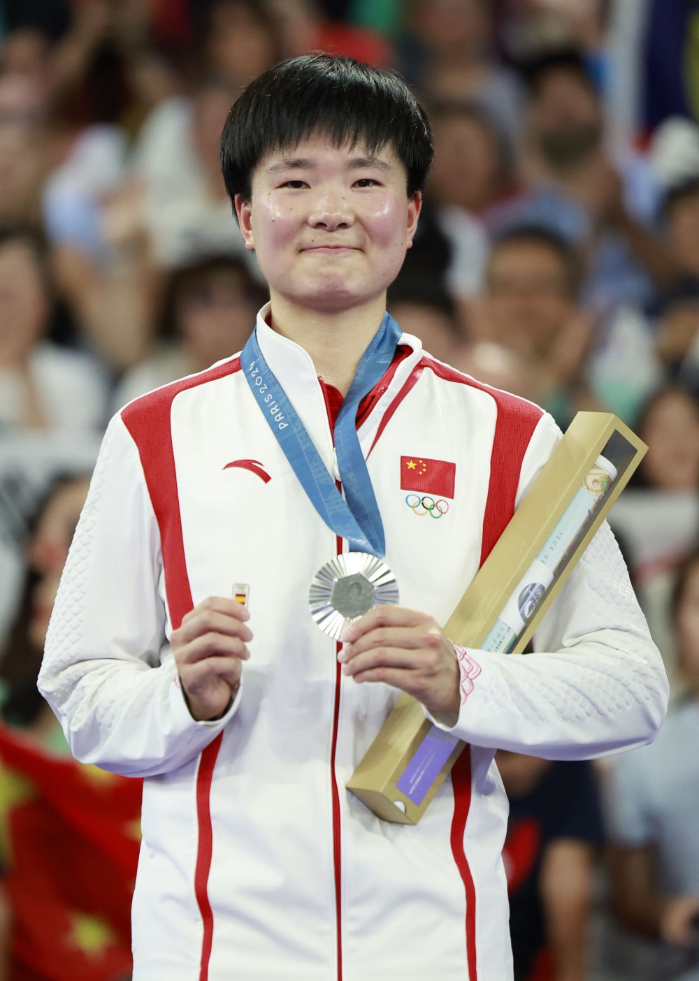 巴黎奧運會羽毛球女子單打亞軍、中國選手何冰嬌在頒獎儀式上一手握著銀牌，一手握著西班牙奧委會徽章（2024年8月5日攝）。新華社記者 任正來 攝