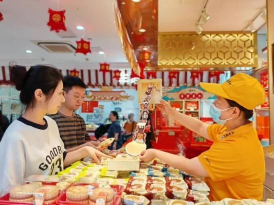 北京稻香村一家門店內，售貨員向顧客展示新上市的月餅禮盒。（受訪者供圖）
