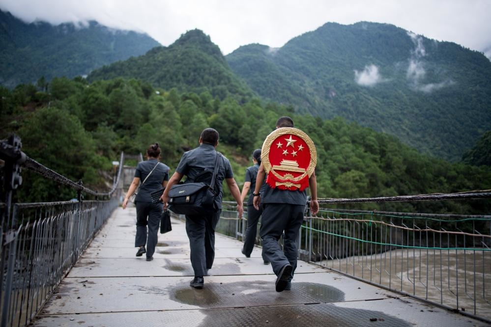 云南省怒江傈僳族自治州貢山縣人民法院法官鄧興背著國徽與同事們跨過怒江（2019年8月30日攝）。怒江高山峽谷眾多，交通不便，為方便群眾、更好地開展法律服務(wù)，背著國徽攀高山、過索橋、躲落石、鉆老林……成為鄧興法官的工作常態(tài)。新華社記者 江文耀 攝
