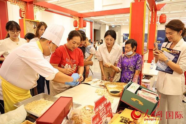 演出前，在天津桂發(fā)祥十八街麻花制作技藝非遺體驗(yàn)展臺前，泰國民眾體驗(yàn)天津麻花制作。人民網(wǎng)記者 楊一攝