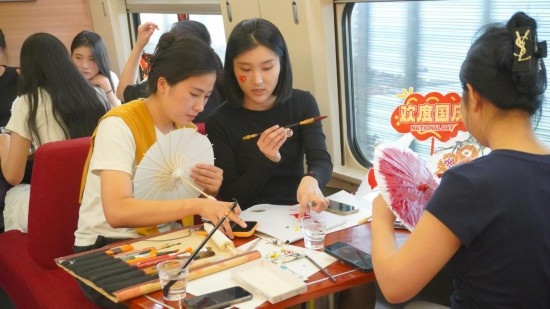 10月1日，旅客們在G1634次列車上給油紙傘作畫。新華社記者周義 攝
