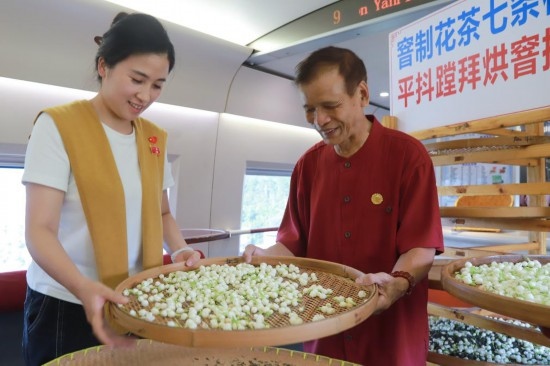10月1日，福州市茉莉花茶窨制工藝代表性傳承人張子建與旅客在G1634次列車上制作茉莉花茶。新華社記者周義 攝
