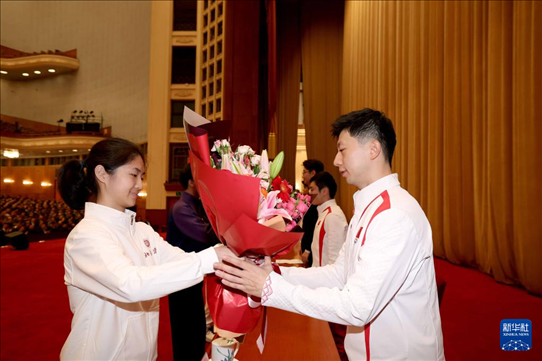 11月15日，一名學生代表在報告會上向乒乓球運動員馬龍（右）獻花。新華社記者 李明 攝