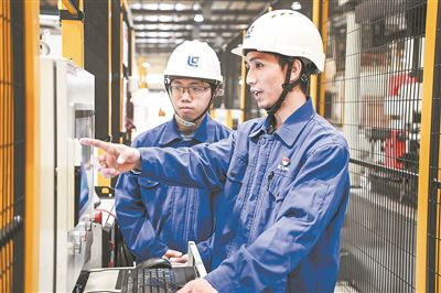 在廣西柳工機(jī)械股份有限公司生產(chǎn)車間內(nèi)，一名高級技師（右）給徒弟講解數(shù)控設(shè)備操作細(xì)節(jié)。新華社記者 曹祎銘攝