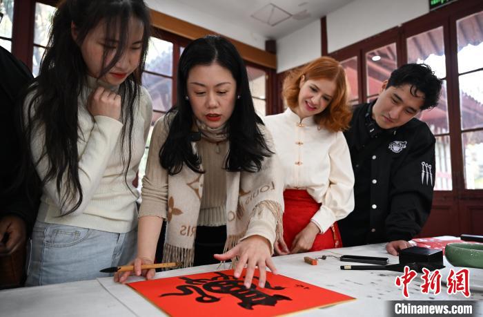 1月20日，西泠印社社員李硯（左二）為外籍留學(xué)生講述蛇年福字貼創(chuàng)作靈感。當(dāng)日，來自巴西、馬來西亞、加納、哈薩克斯坦的外籍留學(xué)生在浙江杭州西泠印社體驗(yàn)福貼、春聯(lián)和篆刻，感受古老的中國(guó)傳統(tǒng)文化。中新社記者 王剛 攝