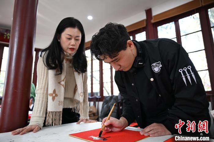 1月20日，外籍留學(xué)生在西泠印社社員李硯指導(dǎo)下寫福。當(dāng)日，來自巴西、馬來西亞、加納、哈薩克斯坦的外籍留學(xué)生在浙江杭州西泠印社體驗(yàn)福貼、春聯(lián)和篆刻，感受古老的中國(guó)傳統(tǒng)文化。中新社記者 王剛 攝