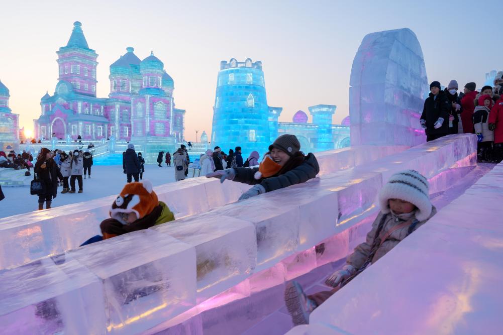 游客在哈爾濱冰雪大世界園區(qū)內體驗冰滑梯。新華社發(fā)