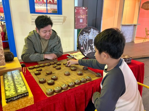 柯秋楓與市民下椰雕象棋。人民網(wǎng) 陳葉欣攝