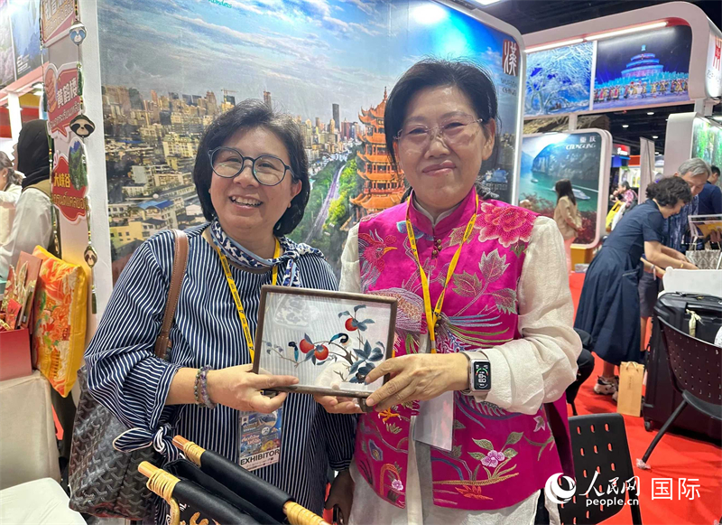 中國“大冶刺繡”傳承人劉小紅（右）參加泰國國際旅游展，向觀眾介紹中國非遺刺繡針法。人民網記者 簡承淵攝