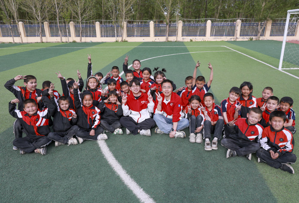 4月23日，在新疆克州阿圖什市哈拉峻鄉(xiāng)謝依特小學(xué)，支教教師王俊文（中左）、李軻凡（中右）和學(xué)生在一起。