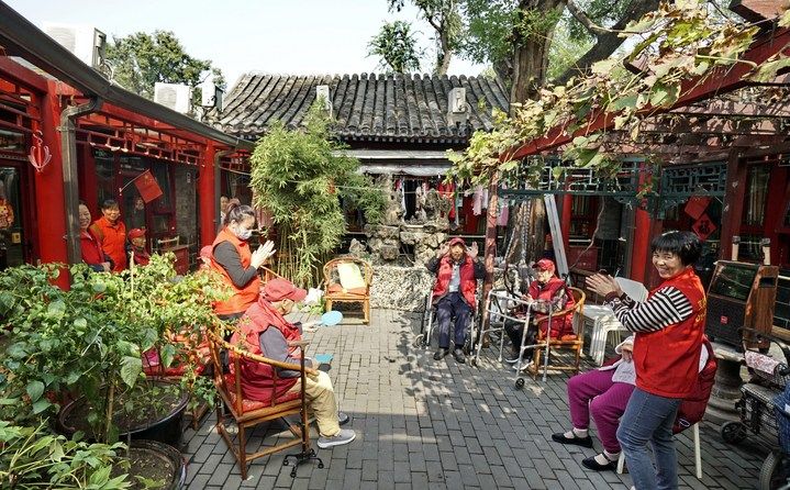 2024年10月12日，鐘樓灣胡同的老年人在社區(qū)內(nèi)的四合院養(yǎng)老驛站休閑。2017年起，北京市先后開(kāi)展了兩輪背街小巷環(huán)境整治提升行動(dòng)，完整保留了中軸線生活建筑群的歷史信息，并根據(jù)居民的生活和居住方式進(jìn)行適配化的更新和改造，極大地改善了生活環(huán)境。2023年鐘樓灣胡同被評(píng)為“北京最美街巷”。